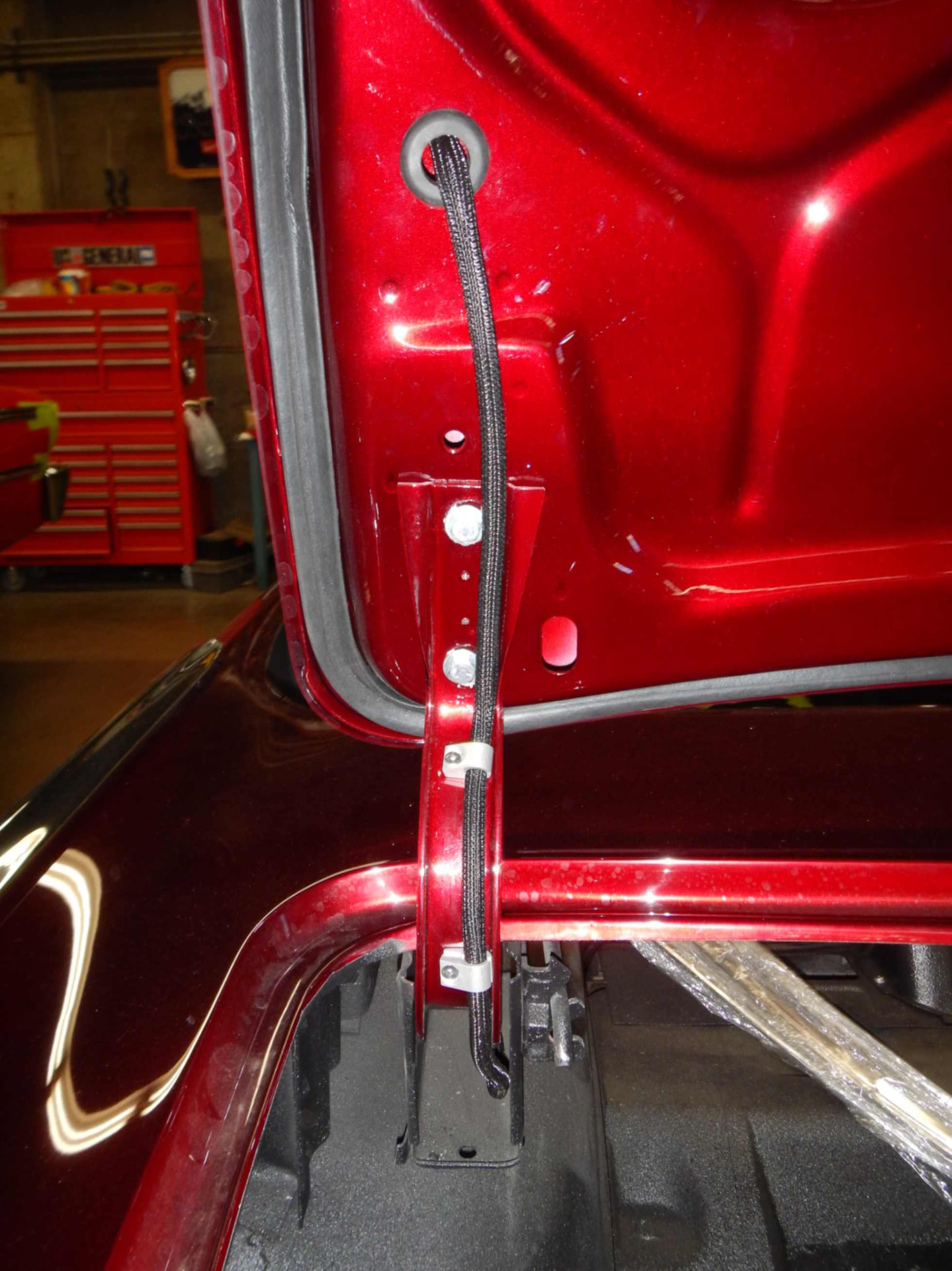 Convertible top latch and cable detail against the fresh candy-red paint