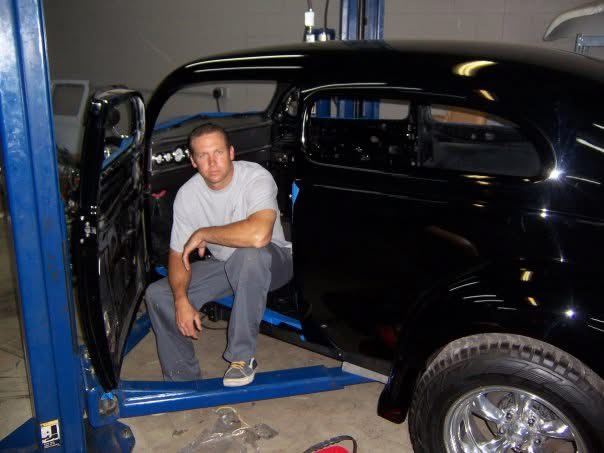 Bodie seated in a classic car in the shop